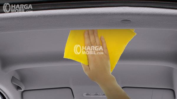 gambar seorang wanita sedang membersihkan plafon mobilnya dengan handuk tangan berwarna kuning
