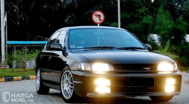 Gambar ini menunjukkan mobil Toyota Great Corolla 1992 tampak warna hitam bagian depan